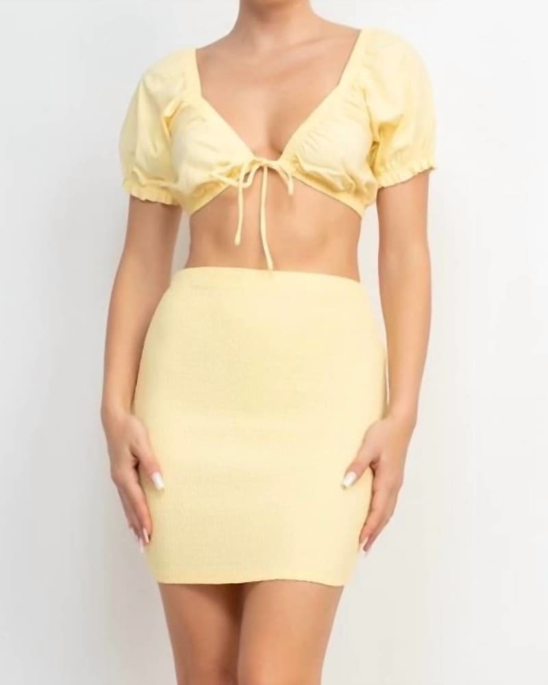 Front of a model wearing a size Large Front Tie V-Neck Crop Top & Smocked Skirt Set In Baby Yellow in Baby Yellow by Haute Monde. | dia_product_style_image_id:354370